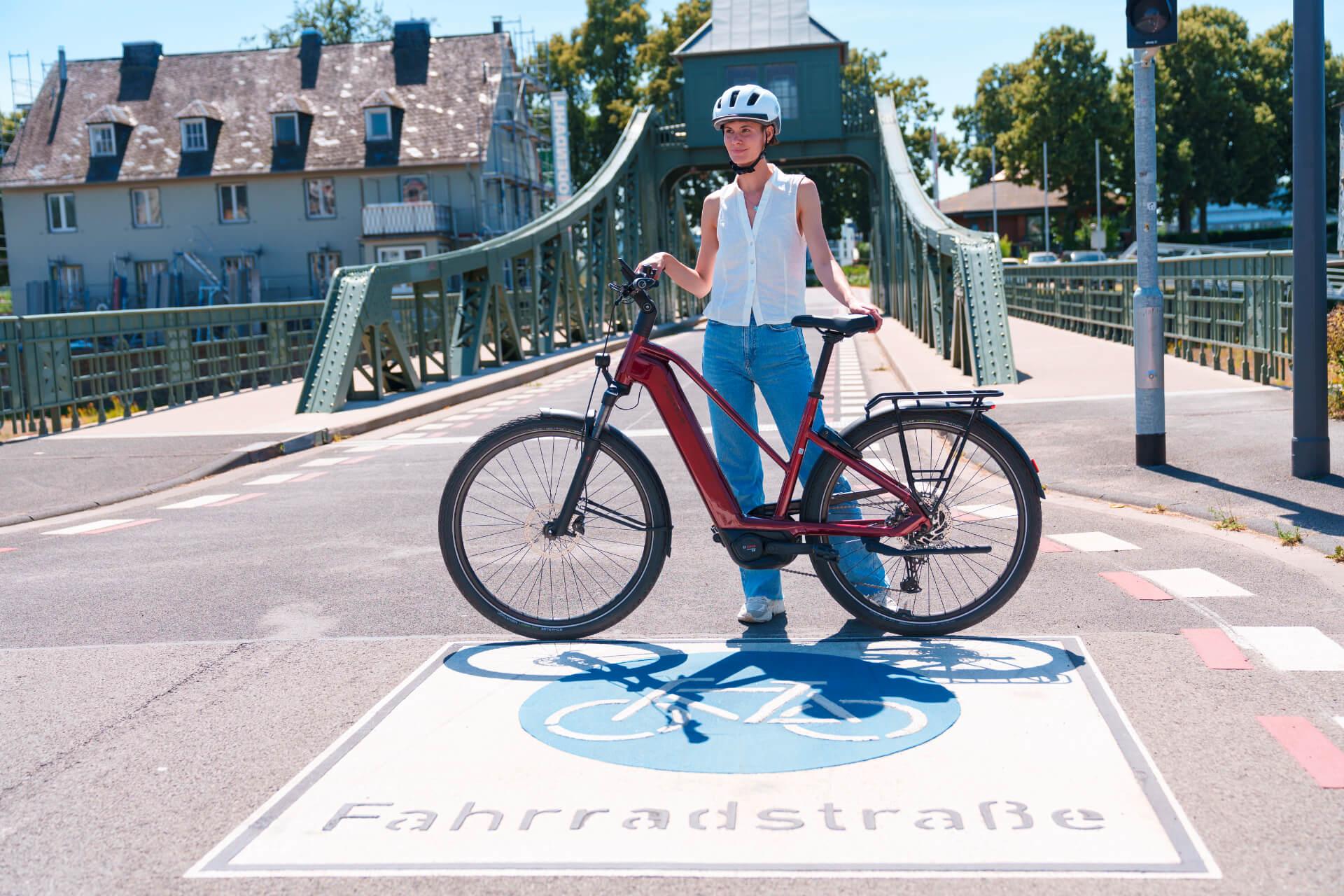 Nő áll egy kerékpársávon egy bordó ebike-ot fogva